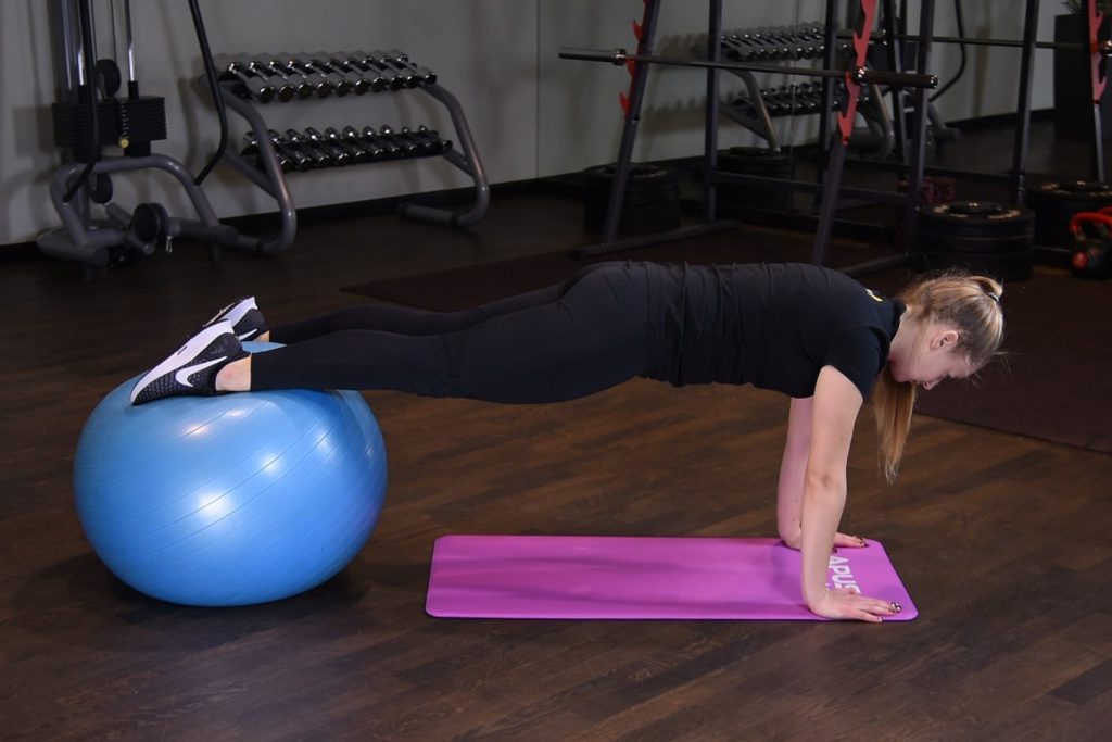 Deska z wyprostowanymi ramionami oraz stopami na piłce do ćwiczeń