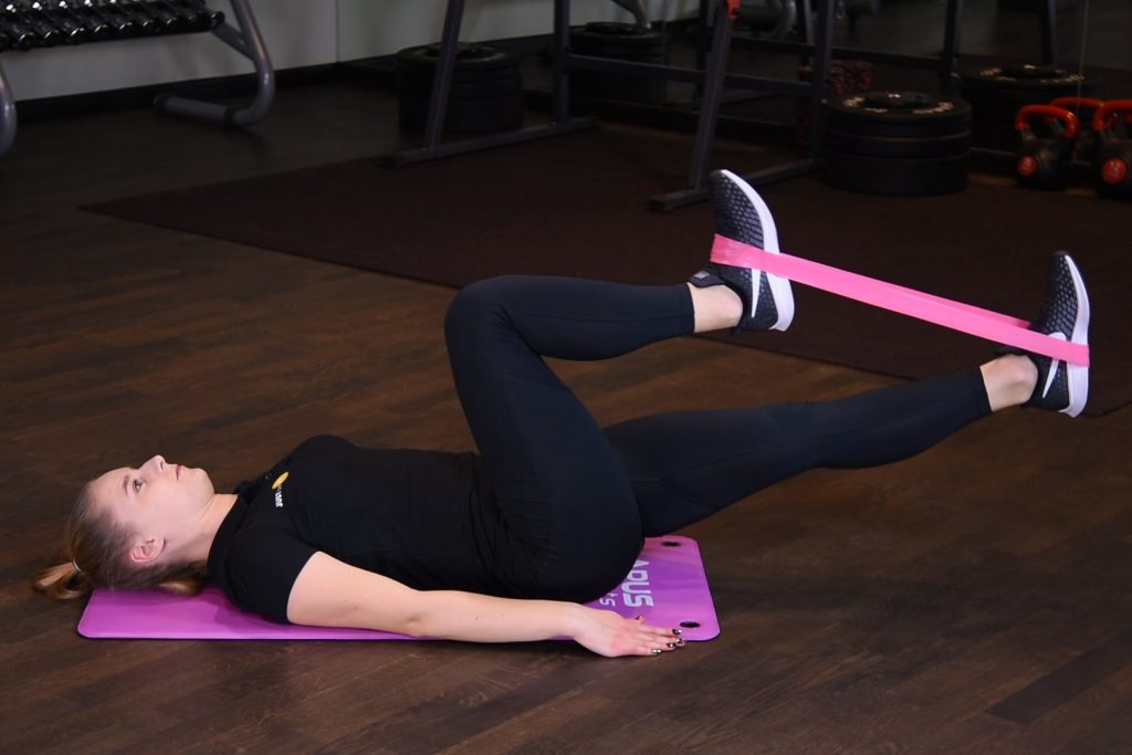 Rowerek w leżeniu tyłem z gumą mini band na stopach