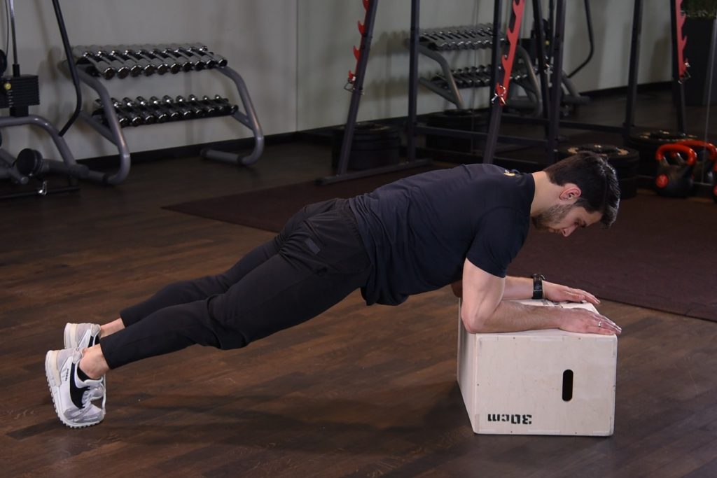 Plank z ramionami na podwyższeniu