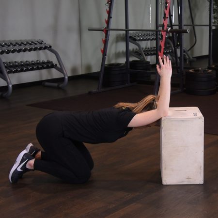 Rozciąganie mięśni najszerszych grzbietu i tricepsów w klęku z łokciami na podwyższeniu