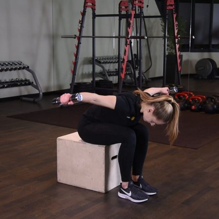 Ćwiczenie unoszenie hantelek na boki w opadzie tułowia siedzac i pochylajac sie w kolana