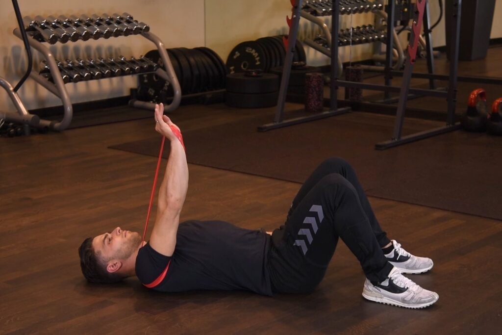 Wyciskanie jednorącz gumy mini band leżąc na ziemi